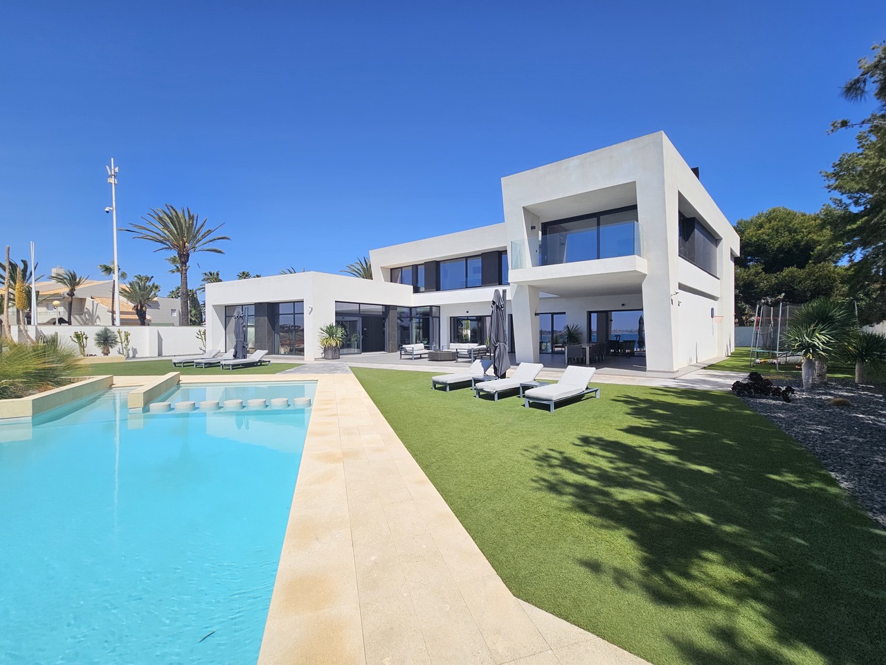 Modern cubist beachfront villa with pool and lawn at Cabo Roig
